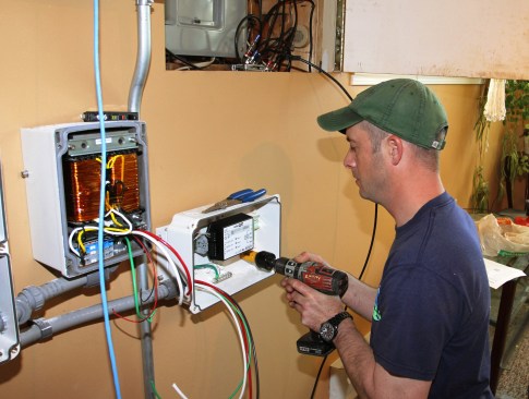 Millette bores a hole in the StorEdge meter enclosure so he can route a power feed to the meter from the existing distribution panel.