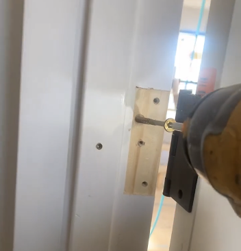 Once the jamb is plumb, the author adds structural screws behind the hinges to take the weight of the door.