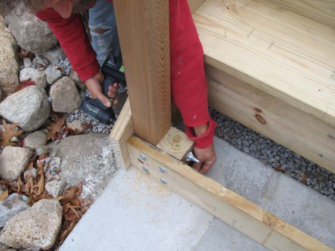 The bottom guardrail posts on a set of stairs need to be secured well to prevent them from becoming wobbly over time.  Bracketed stringers are taller and provide more attachment surface than cut stringers so they tend to be more stable front to back.  But to keep the posts from moving in and out (side to side?) I use a block and screw system for deck guard posts I first learned from FastenMaster about 6 years ago using ThruLok nutted screws.  The 4x4 posts and blocks cut the length of the riser board height are ThruLok'd to the structural riser. Longer ThruLok screws are driven through the stringer, post and block.  