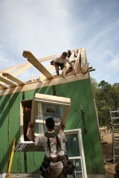 12:28p Framers are setting rafters while another crew installs the windows in the completed walls below.