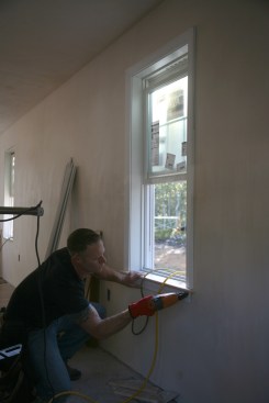7:59a Crewmember trims out a window in the living room.