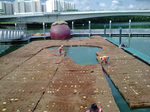 Workers assemble a floating island on a waterway in Singapore.