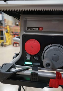 The large red paddle button to stop the saw is nice. To start the saw, you pull the red paddle out, then activate the main switch (grey button with white circle). To deactivate the brake cartridge (or put the saw in "bypass mode") is required when cutting wet material, such as pressure-treated lumber, which the author's crew does frequently. To do this requires turning the bypass switch (to right of main power switch) while pulling the red paddle button out. The author would prefer a simple on-off switch for the safety system.