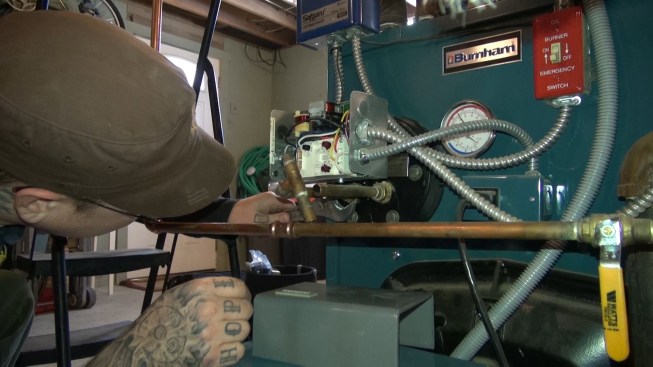 He tightens down the plate on the tankless coil so the gasket won’t leak.
