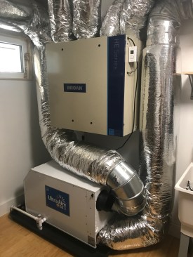 Most ERVs like this one (upper piece of equipment) have ports for standard 4- or 5-inch ductwork. Note that this system includes the indoor coil (lower piece) for a dedicated dehumidifier, which will be needed in most locations to address latent loads.