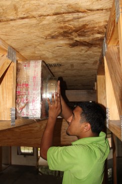 Installer Luis Ventura inserts a tap collar for a flex-duct connection to a duct board box.