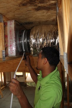Then he slips the duct liner over the collar, and tightens a cable tie over the joint using a tensioner.