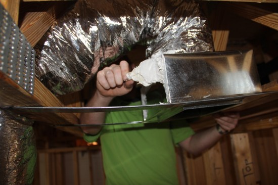 ... and butters the seams of a register boot with mastic to ensure airtightness.