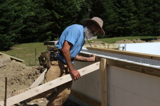 The 2x4s, placed inside and out, protected the top edge of the form from damage during the pour. I then ran a diagonal brace off the outside 2x4 about every 4 feet to a form stake driven in the ground.