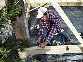 We located the joists just above the soil level, and let the band joist into the repurposed  8”x8” cedar posts (we held the band joist off the masonry wall with pressure treated spacers). 

