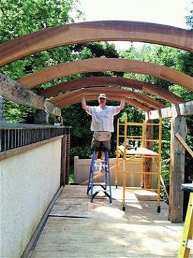 When we installed the beams, we connected one of them to the top of the masonry wall with stainless steel all-thread that was epoxied through the slate capstones and into the concrete-filled top course of block. We fastened the beam on the opposite side to the posts using stainless steel all-thread and barrel nuts placed into the posts and concealed with dowels.