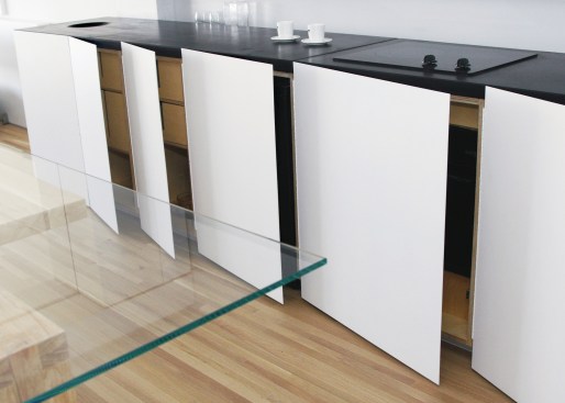 To create more kitchen storage in this 550-square-foot Chicago studio, Vladimir Radutny Architects concealed drawers and shelves behind flat panels along the countertop.