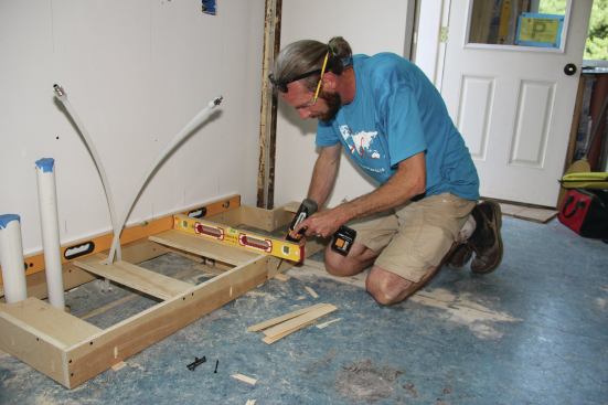 One option for out-of-level floors is to first level and fasten a ladder base, then install plain base boxes on top of it.