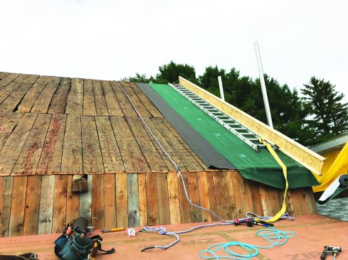 Working from the new shed roof, the crew stripped off old metal roofing.