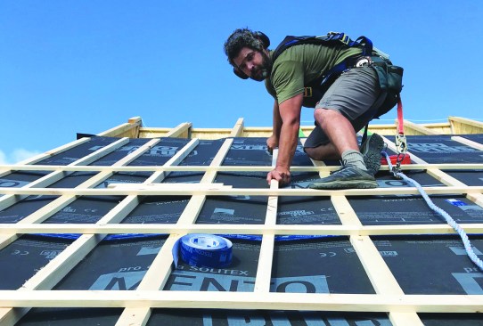 A crosshatch of strapping ventilates the new roof buildup from above.