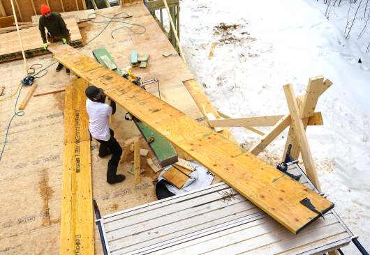 Carpenters mark, measure, cut, and place 20-inch LVL members as they assemble a high-capacity engineered wood structure in place, piece by piece.