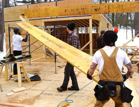 Carpenters mark, measure, cut, and place 20-inch LVL members as they assemble a high-capacity engineered wood structure in place, piece by piece.