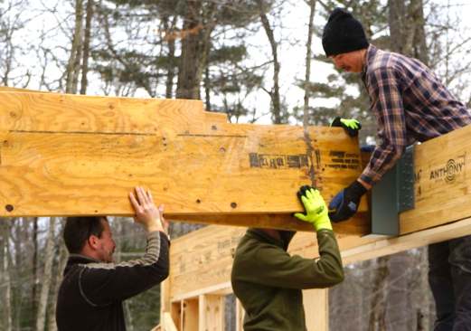 Carpenters mark, measure, cut, and place 20-inch LVL members as they assemble a high-capacity engineered wood structure in place, piece by piece.