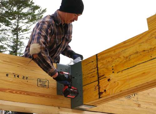 Carpenters mark, measure, cut, and place 20-inch LVL members as they assemble a high-capacity engineered wood structure in place, piece by piece.