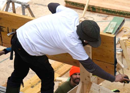 With the first LVL in place on the post, Friel checks the overhang of the beam. This portion of the LVL support member will be buried in the home's foot-thick superinsulated wall.