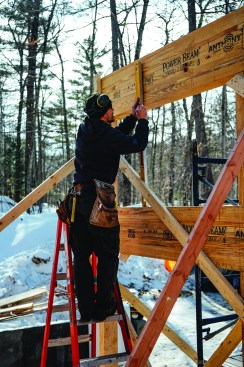 Carpenters Alex Strugatskiy and Will Kessler framed in the window opening between two large glulam carrying beams with 2x6 lumber. Strugatskiy laid out stud locations.