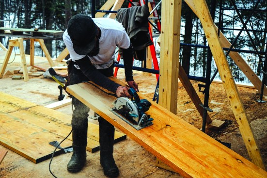 He laid out and cut a notch on the end of the beam to match the framing of the flat-roofed section at the front of the house.