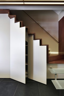 Stepped shelving in staircase of this D.C.-area home remodel by KUBE Architecture capitalizes on an otherwise unused space.