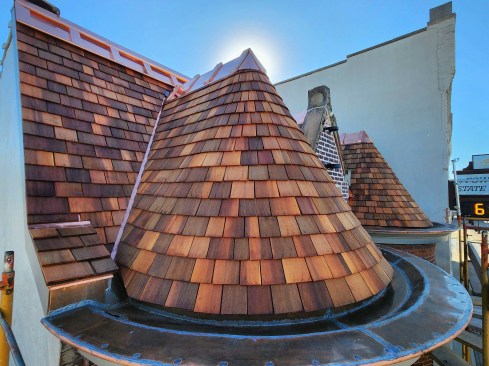A view of the completed roof shows the ribbed ridge caps and soldered copper gutter assembly.