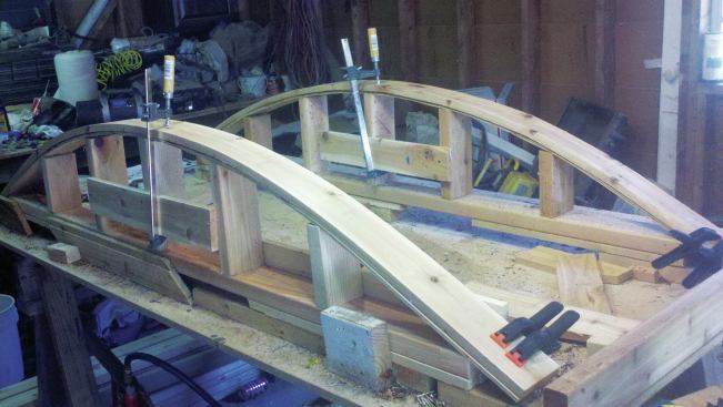 The building jigs are assembled out of 2-by lumber and 1/4-inch plywood. Here, curved top and bottom rails are clamped to the jigs.