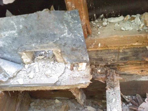 This photo shows significant damage to wood framing from water intrusion at a through-wall scupper. Poor or missing details—including a lack of exterior counterflashing over the scupper and poor installation of the weather-resistant barrier—allowed water to leak in from the exterior side. In addition, the scupper was initially installed with the drain-end of the tube higher than the deck. This caused water to pool in front of the scupper, and eventually that water seeped in past the poorly applied deck coating and around the scupper.