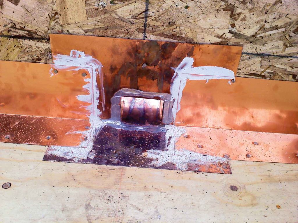 Note that the L-flashing laps over the scupper flanges and that these laps are bedded in a polyurethane caulk.