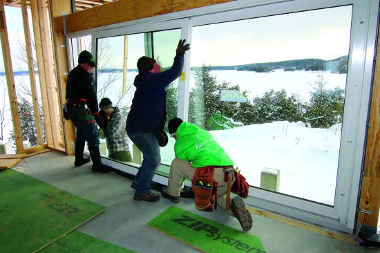 Structural screws are set into the framing through predrilled holes in the jams. Then the crew places the sliding doors onto their tracks.