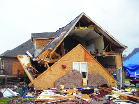 A gable end has been torn away from the roof and wall in one piece.