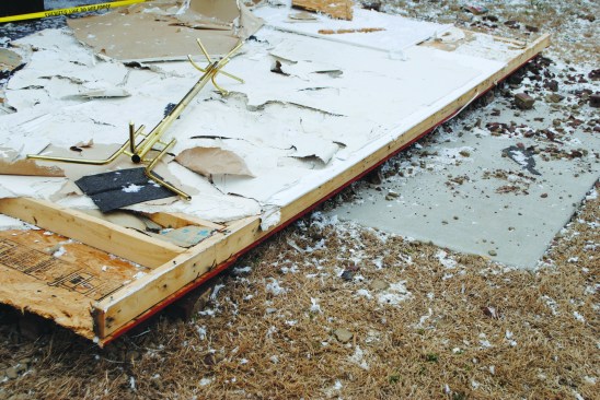 An intact wall lies on the ground after separating from the sill.