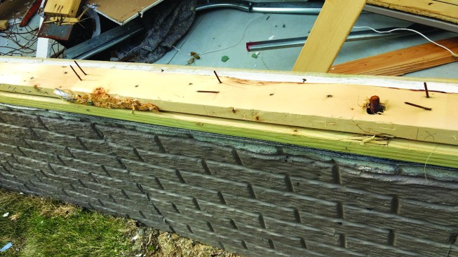 A sill plate sits attached to the foundation where a wall separated from it.
