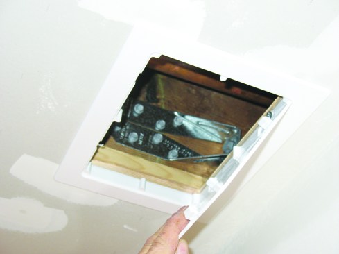 When there’s a finished ceiling, cut a hole to match the size of the planned access panel and bore the rod hole through the ledger and rim joist from the outside. A right-angle drill/driver may be needed to screw the anchor to the side of the joist.
