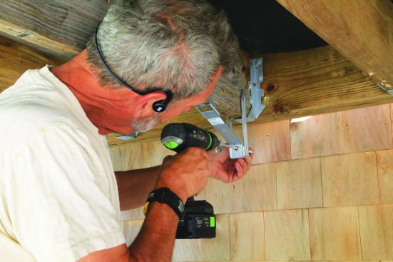 The legs screw to the sides of the deck joist to form a triangle; the plate screw can be driven afterward.