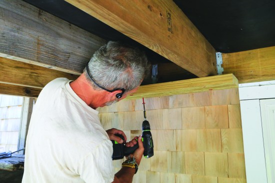 To fasten ties to wall studs rather than a plate, the author installs 2x8 blocking across the bottom of the deck joists.