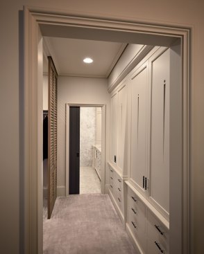 The walkway to the bathroom features a custom linen press cabinet and cypress louvered doors separating the walk-in closet.See the full article about this award-winning project.