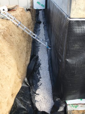 To ensure good drainage, a perforated PVC perimeter drain covered in stone and wrapped with geotextile fabric was installed before backfilling the foundation.