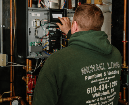 Michael Long adjusts the controls on his 155,000 Btu Aspen boiler. The unit heats water pumped through about 14,000 lineal feet of tubing throughout the 4,000-square-foot house, including a three-car garage.