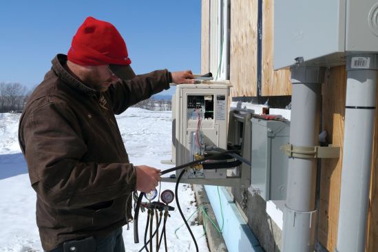 During commissioning, gauges are hooked up to the compressor to monitor evacuation and add R410A refrigerant. Here the tech prepares the 4-conductor wire that runs to the indoor head.