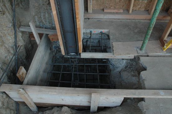Install anchorage. The anchorage can now be installed at the column base plates and suspended in the open footing. Be sure that the connection has nuts and washers above and below the base plate. The anchors should extend at least one thread beyond the upper nut for easy inspection that all threads in the nut are filled.