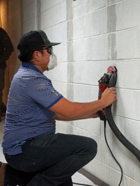 After the layout is complete, a helper grinds these areas free of dirt and paint.