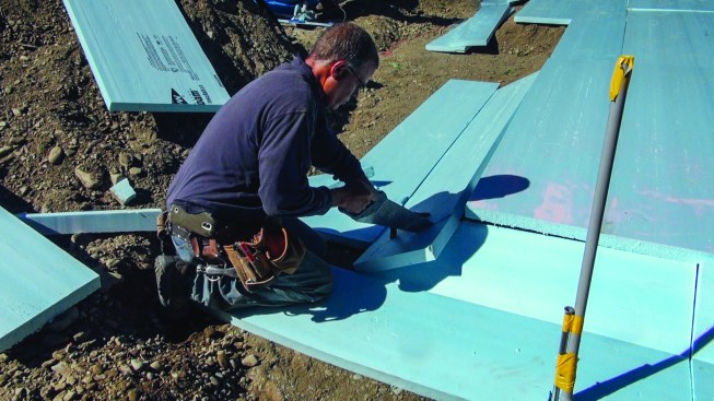 Above, a concrete contractor fits 2-inch extruded polystyrene to the gravel base for the foundation slab.