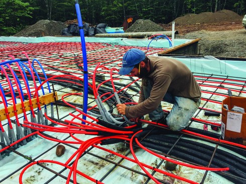 Kelly and Dwyer ran the extensive tubing for the home's innovative radiant slab heating system themselves, as a cost savings and a learning opportunity. Main runs from the system's manifold were insulated. Here, Kelly works tubing into a bent conduit at the manifold connection.