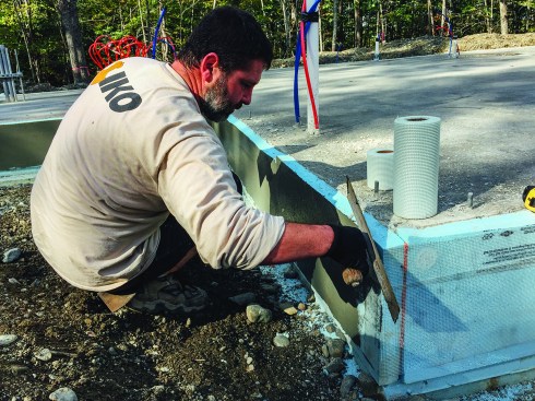 Local contractor Sean Kinney applies acrylic thin-coat stucco to the vertical XPS slab-edge insulation. This detail was economical and simple, but the R-10 slab edge represents a relative weak point in the building's thermal envelope, noted Kelly.