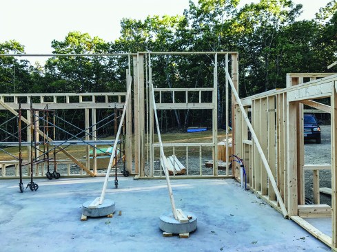 To avoid the risk of piercing the plastic hydronic tubing in the slab, the framing crew nailed temporary wall bracing to pre-cast concrete footing “cookies.” This workaround proved only partially effective, said Dwyer, because the cookies moved slightly on the slab's slippery surface.