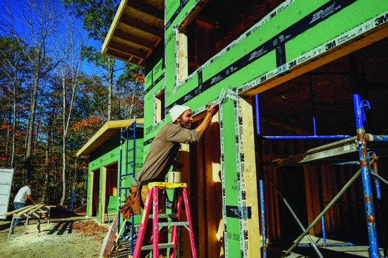 Taped ZIP sheathing forms the wall system's air control layer. Above, David Kelly tapes the sheathing to the window framing to air-seal that juncture using 3M 8067 tape.