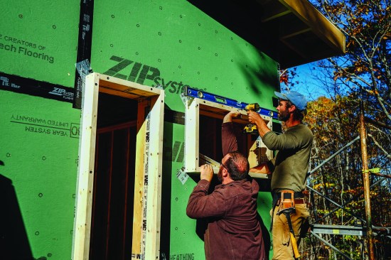 Above, David Kelly and carpenter Rick Martin apply a 4-inch buildout to a window rough opening, adding the wall depth needed to accomodate two inches of exterior-applied XPS foam insulation, plus wood strapping and fibercement cladding panels.